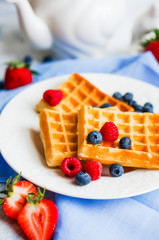 Belgian waffles with berries on rustic background