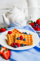 Belgian waffles with berries on rustic background