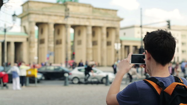 Young teenager taking photo with his smartphone of Brandenburg g