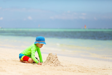 Fototapeta na wymiar Caucasian boy building sand castle on tropical beach