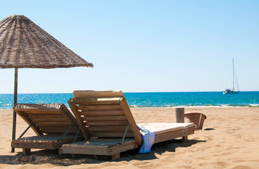 Sunbeds and rattan parasols on sandy seaside.