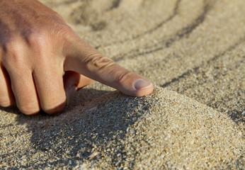 Woman hand and sand.