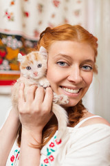 Fototapeta na wymiar Red-haired girl with a red kitten