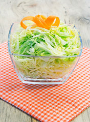 Bowl of green cabbage salad decorated with carrot.