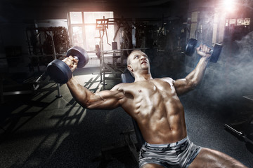 Athlete in the gym training with dumbbells