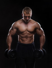 Naklejka na ściany i meble Handsome muscular man working out with dumbbells
