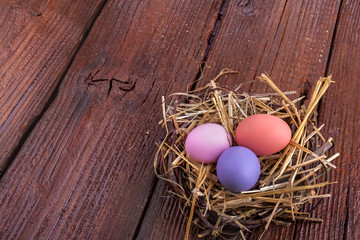 Colorful Easter eggs in the nest on the wooden table