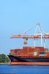 Container stack and ship under crane bridge