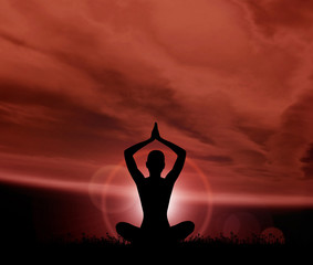 Silhouette of a young woman meditating outdoors