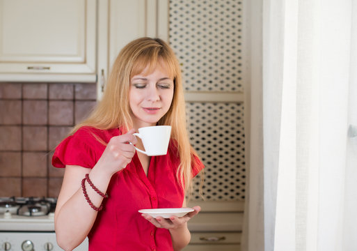 Woman with cup of coffee or tea in the kitchen. Morning coffee.
