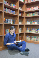 young student reading a book at the library