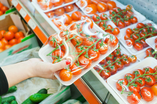 Packaged tomato with woman hand in the supermarket