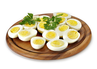 Sliced ​​boiled eggs and parsley on wooden tray.