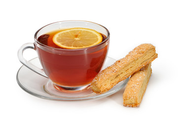 Glass cup with tea and a lemon on a glass saucer and cookies.