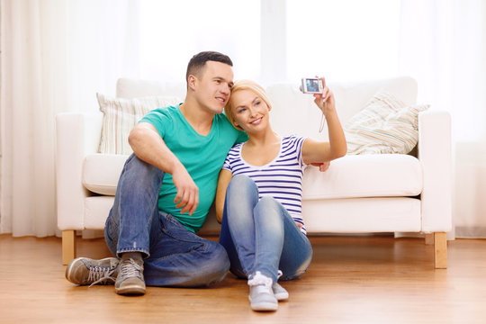 smiling couple taking picture with digital camera
