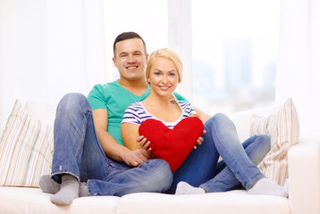 smiling happy couple with red heart at home