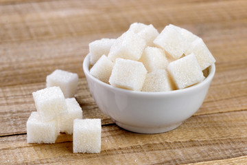 Sugar cubes in bowl on wooden table - 63680778