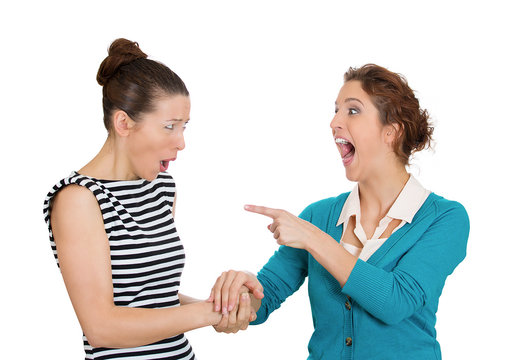 Young woman making fun of her friend laughing pointing 