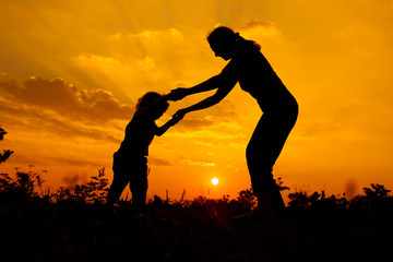 silhouette of a mother and son who play outdoors at sunset backg