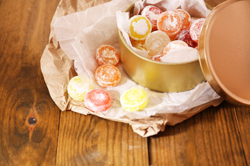Sweet candies in metal can, on wooden background