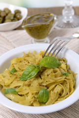 Delicious pasta with pesto on plate on table close-up