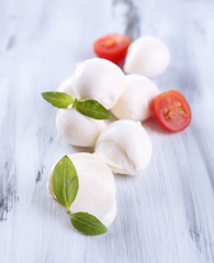 Tasty mozzarella cheese with basil and tomatoes, on wooden