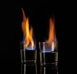 Glasses with burning alcohol on black background