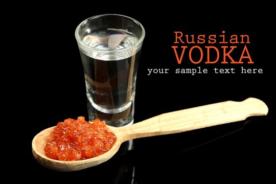 Glass of vodka, red caviar  isolated on black