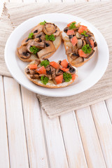 Delicious bruschetta with mushrooms on plate on table close-up