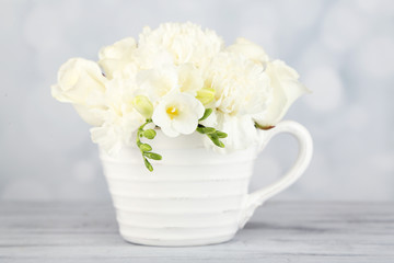 Beautiful spring flowers in cup on light background