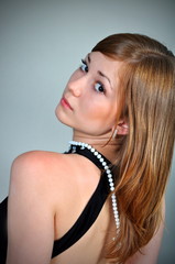 Pretty girl looks mysteriously sitting on a chair. Studio.