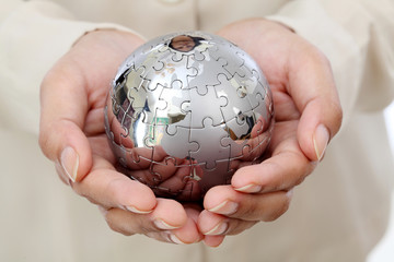 Business woman hand holding jigsaw puzzle globe