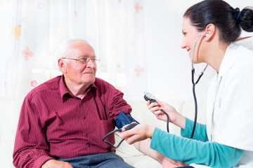 Young Doctor Measuring Blood Pressure Of Senior Patient
