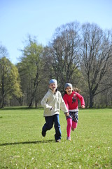 Boy and girl are running on the grass