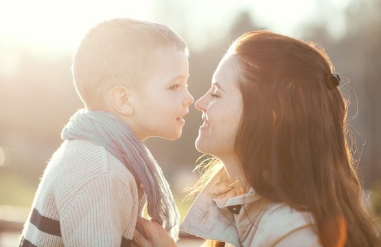 Young mother kissing child outdoor