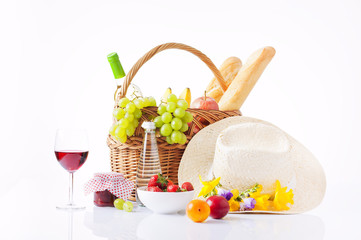 picnic basket with bottle of wine,fruits, bread and summer hat