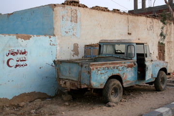 Old SUV in the desert oazis town by the blue building