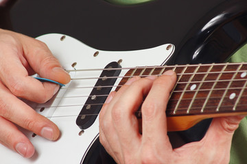 Rock guitarist put fingers for chords on electric guitar closeup
