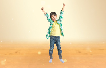 Lucky brunette kid over isolated ocher background