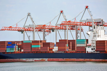 Container stack and ship under crane bridge