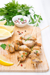 skewers of chicken with lemon and parsley on a wooden board