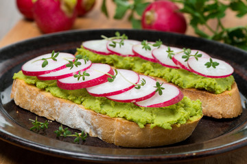 toasted ciabatta with pate of avocado and fresh radish, close-up