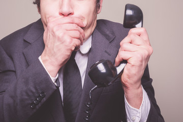 Businessman on phone covering his mouth