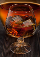 Whiskey with ice on dark wooden background