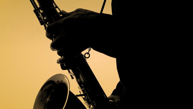 Man playing sax in silhouette. Close-up