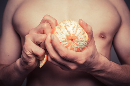 Closeup on athletic man peeling an orange