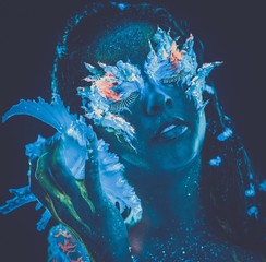 Woman with body art glowing in ultraviolet light