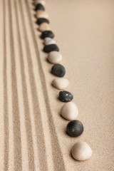 Fototapeta na wymiar Stripe of white and black stones lying on the sand