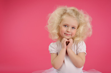 Little girl in a tutu skirt on pink background