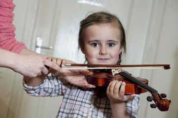 cute preschool girl learning violin playing